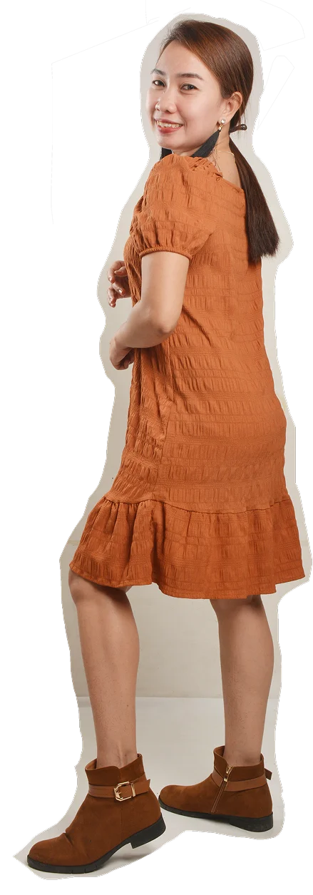 Whitney standing, in a rust dress and brown ankle boots